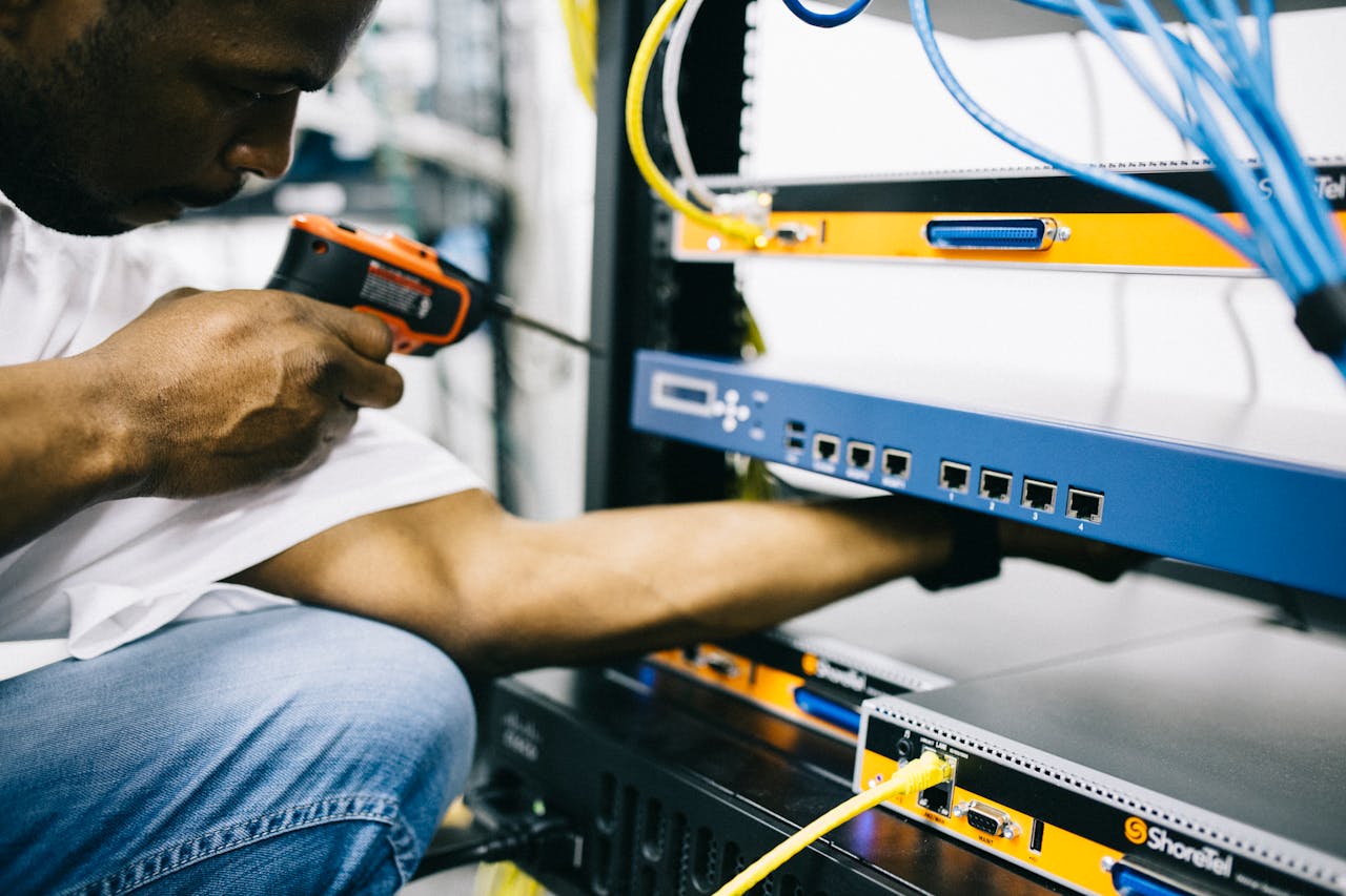Services Side view crop concentrate African American male mechanic in jeans and white shirt using screw gun while working with hardware